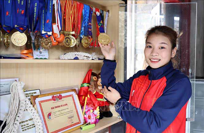 Vận động viên Triệu Thị Phương Thủy bên tủ huy chương các loại mà cô đã giành được. Ảnh: Trung Kiên/TTXVN